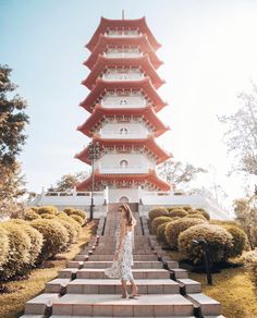 a woman standing on steps in front of a tall pagoda