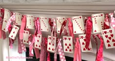 valentine's day cards hung on a mantle with pink and red ribbons hanging from them