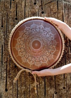 two hands holding a brown plate on top of a wooden table