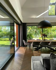 a dining room with wooden floors and glass doors leading to an outside deck that overlooks a lush green yard