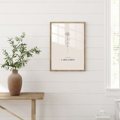 a vase sitting on top of a wooden table next to a wall mounted art piece