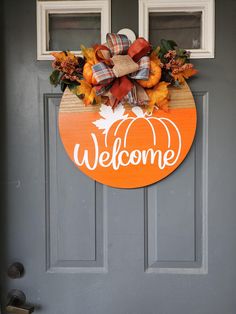 a welcome sign on the front door of a house with pumpkins and fall leaves