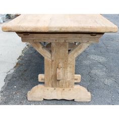 a wooden table sitting on top of a cement floor next to a sidewalk with no one around it