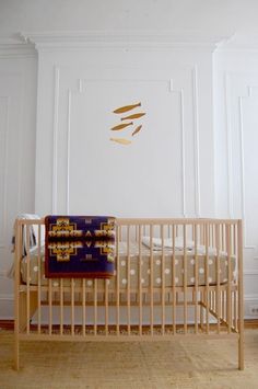 a baby crib with a blanket on top of it next to a wall mounted clock