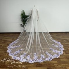 a wedding veil with purple flowers on the bottom is hanging in front of a plant