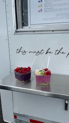 two small cakes with strawberries on top sit on a table in front of a trailer