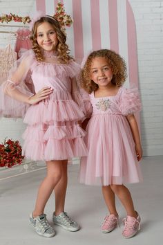 Introducing the girls' pink haze Brielle dress by the renowned designer brand OohLaLa Couture, available in sizes 12 months to 14 years. Designed with impeccable style, the Brielle dress boasts a trapezium neckline that exudes sophistication and a touch of uniqueness. The puff sleeves add a playful charm to the dress, making it a delightful choice for any occasion. The highlight of this dress is the exquisitely embroidered bodice, which showcases intricate craftsmanship and attention to detail. As your child twirls and moves, the dreamy tulle skirt of the Brielle dress dances with her, creating a whimsical and ethereal effect. The Brielle dress is versatile enough to be worn for various special occasions, from weddings to birthdays and beyond. It's a timeless addition to your wardrobe that Tulle Dress Short, New Cinderella, Pic Poses, Embroidered Bodice, Pink Dresses, Feather Dress, Tea Parties, Dance Dresses, Hair Designs