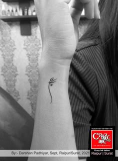 a woman's arm with a small flower tattoo on the left side of her wrist