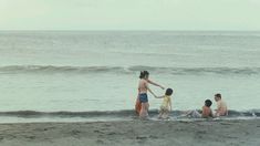 a group of people standing on top of a beach next to the ocean