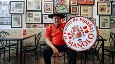 a man sitting in a restaurant holding a sign that says el mayor de espaje