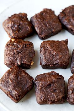 chocolate brownies are arranged on a white plate