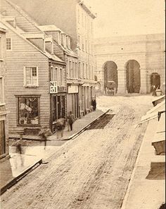 an old black and white photo of people walking down the street in front of buildings