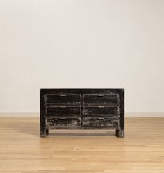 an old black dresser sitting on top of a hard wood floor next to a white wall