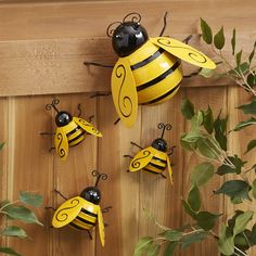 several yellow and black bees are hanging on a wooden fence next to some green leaves