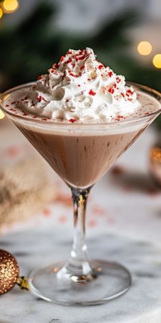 a chocolate martini with whipped cream and sprinkles in a glass on a table