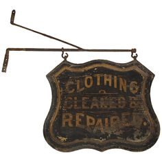 an old sign is hanging from a metal hook on a white background that says clothing clearance and repair