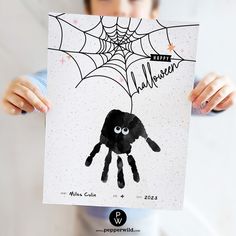 a young boy holding up a halloween card with a spider on it