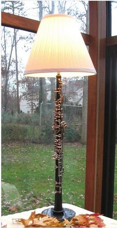 a lamp that is on top of a table in front of a window with leaves