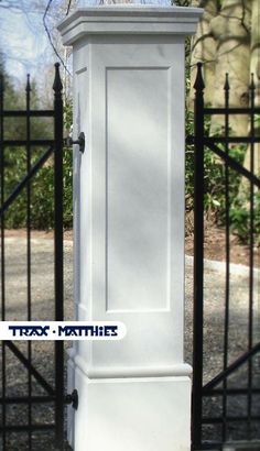 a tall white clock sitting next to a black fence