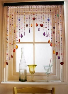 a window with beads hanging from it's side and two vases on the windowsill