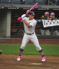 a baseball player holding a pink bat on top of a field