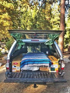 the back end of a truck with a bed and blankets on it's flatbed