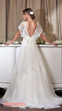 a woman in a white wedding dress standing next to a dresser with flowers on it