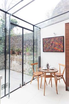 a glass walled dining room with two chairs and a small table in front of it