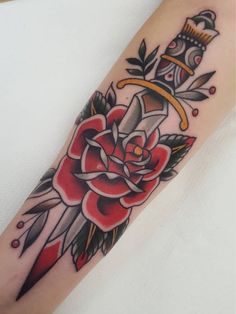 a rose and dagger tattoo on the left arm, with a crown above it's head