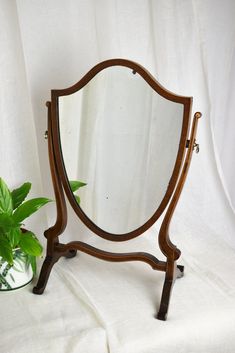 a mirror sitting on top of a wooden stand next to a potted green plant