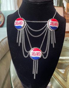 a black mannequin with two pepsi cola bottle necklaces on it