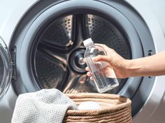 a person holding a bottle near a washing machine