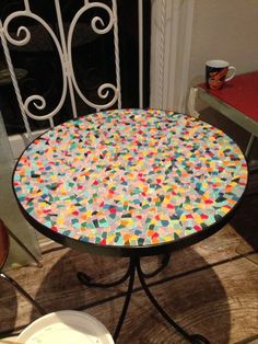 a table that has been decorated with multicolored tiles on it, sitting in front of a door