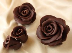 three chocolate roses sitting on top of a white sheet