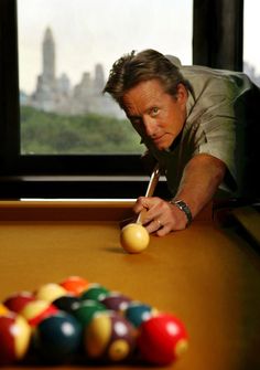 a man leaning over a pool table with a cue in his hand and balls on the ground