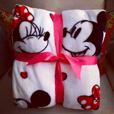 two mickey and minnie mouse blankets wrapped in pink ribbon with red bows on the ends