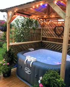 an inflatable hot tub on a deck with string lights and potted plants