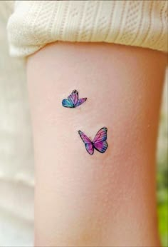 two colorful butterflies on the back of a woman's leg, one is pink and blue