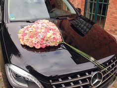 a bouquet of flowers is placed on the hood of a black mercedes benz s - class