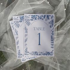 the table numbers are placed on top of each other with blue flowers and leaves around them