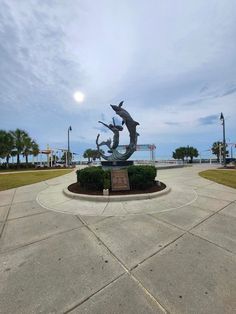 A statue of dolphins and a person located at Myrtle Beach, with the ocean and Boardwalk visible in the background. The sky is overcast, adding a serene atmosphere to the scene. Dolphin Sculpture, Beach Relaxing, Beach Memories, Beach Relax, Playing Golf, Coastal Landscape, Beach Walk