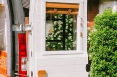 a white van parked in front of a house with flowers on the window sill