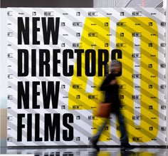 a man walking past a sign that says new director's new films on it