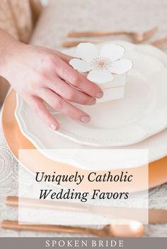 a person holding onto a white plate with flowers on it and the words uniquely catholic wedding favors