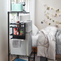 a small refrigerator sitting on top of a metal shelf next to a bed in a bedroom