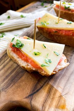 two sandwiches with cheese, tomato and parsley on them