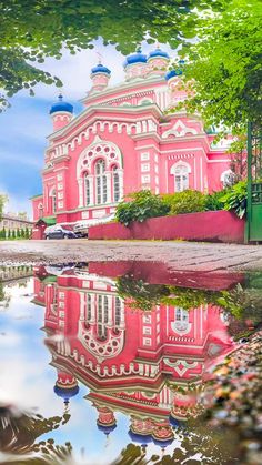 a pink building is reflected in the water