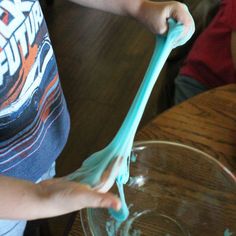 a person holding a blue plastic object over a glass bowl