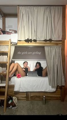 two women sitting on the bottom bunk of a bed