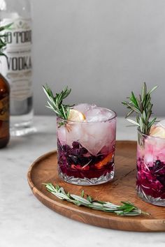 two glasses filled with drinks sitting on top of a wooden tray